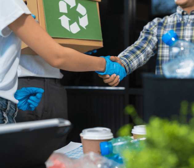 Deux personnes se serrent la main en triant des déchets recyclables.